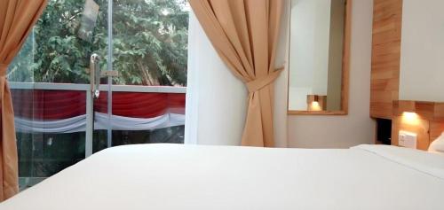 a bedroom with a white bed and a window at An Hotel Jakarta in Jakarta