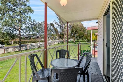 a patio with a table and chairs on a balcony at Moss Vale Village Park in Moss Vale