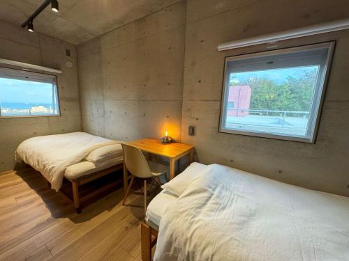 a room with two beds and a desk and a window at 月と太陽 -Sol and Mani- in Nanjo