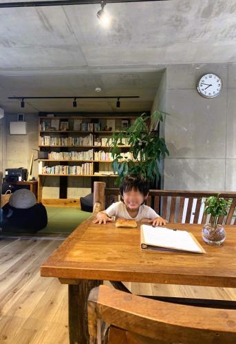 a child sitting at a wooden table with a book at 月と太陽 -Sol and Mani- in Nanjo