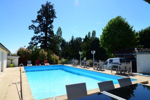a large swimming pool with chairs and a table at La Maison Blanche in Romanèche-Thorins