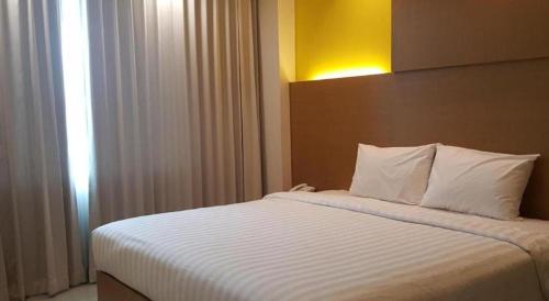 a bedroom with a large bed with white sheets at Kharisma Hotel in Madiun