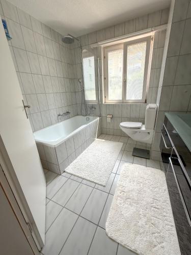 a white bathroom with a tub and a toilet at Room in Homestay with amazing view of lake - Zimmer in einer Gastfamilie mit herrlichem Blick auf den See in Feusisberg