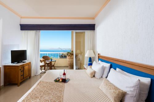 a bedroom with a bed with a view of the ocean at Leptos Panorama Hotel in Kalamaki Chanion