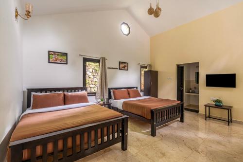 a bedroom with two beds and a flat screen tv at Interlaken in Yedapalli