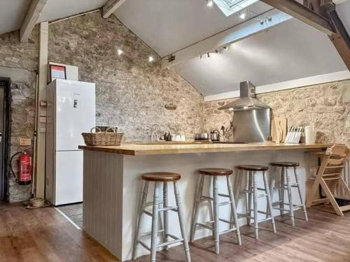 a kitchen with a counter with bar stools and a refrigerator at Kilnsey Wellbeing Barn With Hot Tub, Cold Plunge, Pet Friendly in Kilnsey