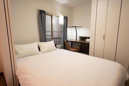 a bedroom with a white bed and a desk at Skytree Tokyo Residence Aoto in Tokyo