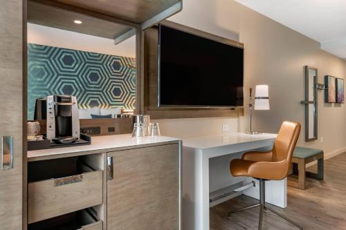a room with a desk with a television and a chair at Cambria Hotel St Petersburg-Madeira Beach Marina in St Pete Beach