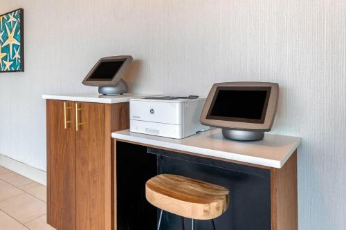 a desk with a computer and a monitor on it at Cambria Hotel St Petersburg-Madeira Beach Marina in St Pete Beach