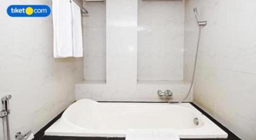 a white bathroom with a tub and a sink at Kenari Tower Hotel in Makassar