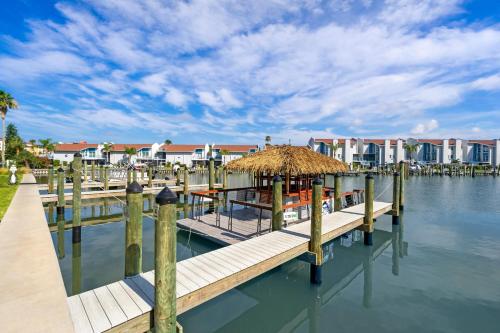 a dock with a hut on the water with houses at Cambria Hotel St Petersburg-Madeira Beach Marina in St Pete Beach