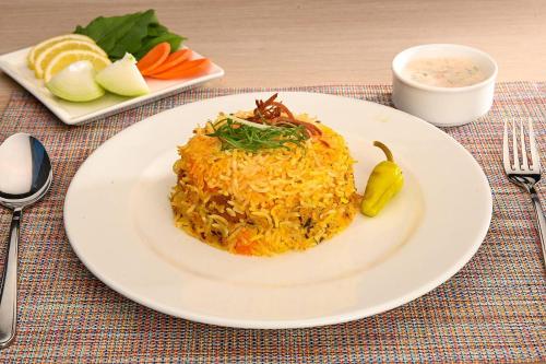 a plate of rice and vegetables on a table at Clarion Hotel Jeddah Airport in Jeddah