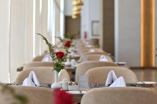 a row of tables and chairs with flowers on them at Clarion Hotel Jeddah Airport in Jeddah