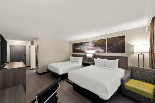 a hotel room with two beds and a chair at Clarion Pointe Rhinelander Downtown in Rhinelander