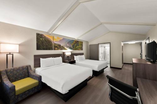 a hotel room with two beds and a chair at Clarion Pointe Rhinelander Downtown in Rhinelander