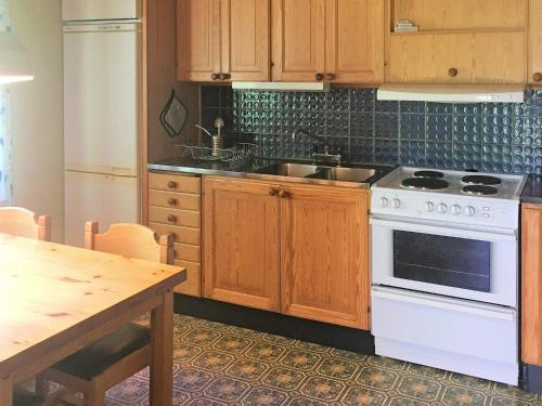 eine Küche mit einem Herd, einer Spüle und einem Tisch in der Unterkunft 4 person holiday home in RÖRVIK-By Traum in Rörvik