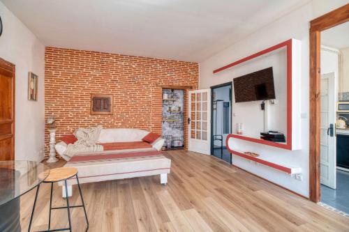 a living room with a couch and a brick wall at L'élite Montauban calme et spacieux in Montauban