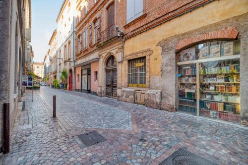 a cobblestone street in a city with a book store at L'élite Montauban calme et spacieux in Montauban