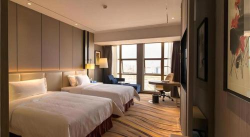 a hotel room with two beds and a desk at Clear Lake Hotel in Shanwei