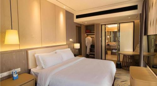 a bedroom with a white bed and a living room at Clear Lake Hotel in Shanwei