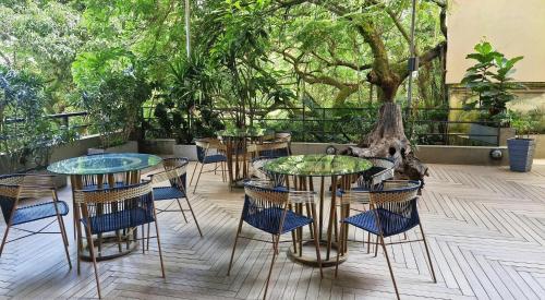 a patio with two tables and chairs and trees at V Grand Hotel, a member of Radisson Individuals in Medellín