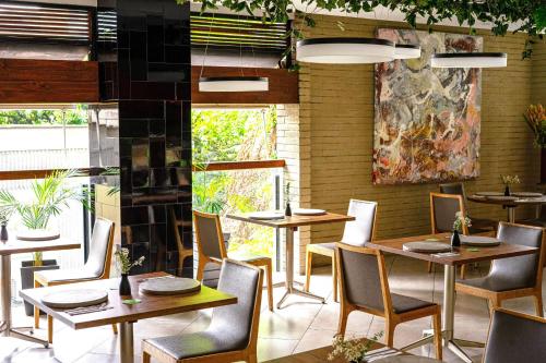 a restaurant with tables and chairs in a room at V Grand Hotel, a member of Radisson Individuals in Medellín