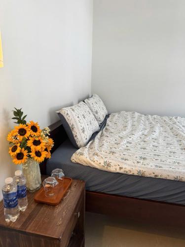 a bedroom with a bed with a table and flowers at Green homestay, Huế in Hue