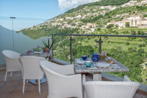 a table and chairs on a balcony with a mountain at Le Perle d'Italia in Ravello