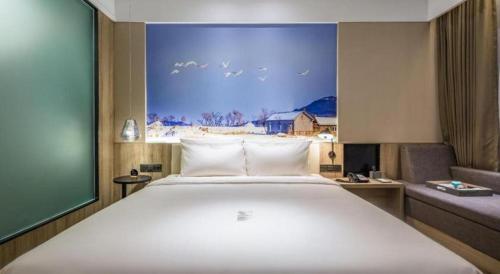 a bedroom with a large white bed and a couch at Atour Hotel Weihai Shidao in Dongshan
