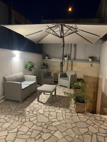 a patio with a table and chairs and an umbrella at Casa Ludogiú in Scorrano