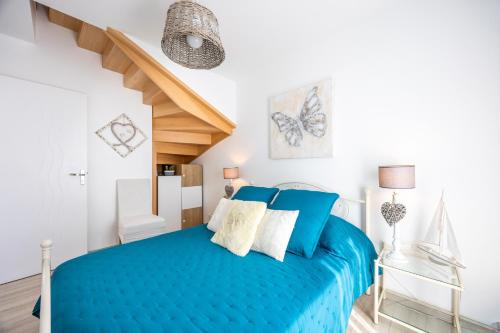a bedroom with a blue bed and a staircase at La Maison du Payré - proche plages in Talmont-Saint-Hilaire