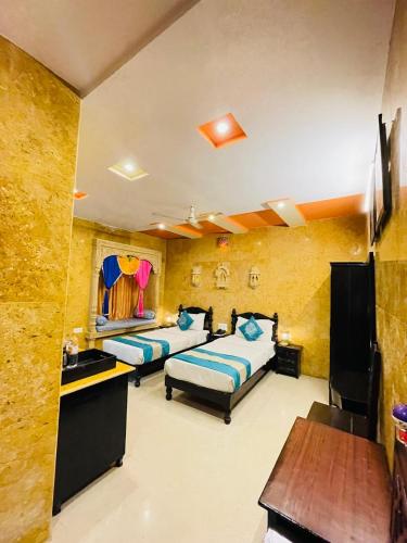 a bedroom with two beds and a desk and a table at Hotel Tokyo Palace in Jaisalmer