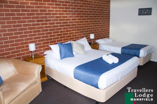 two beds in a room with a brick wall at Mansfield Travellers Lodge in Mansfield