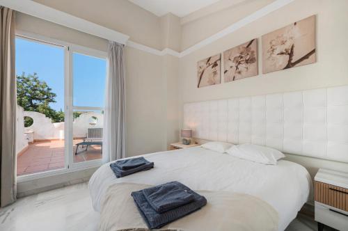 a white bedroom with a bed and a large window at Casa Latifa in Marbella