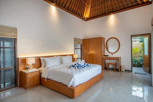 une chambre avec un grand lit et un miroir dans l'établissement Villa di carik ubud, à Ubud