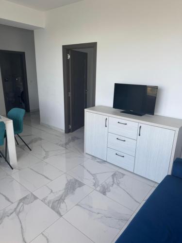 a living room with a tv and a white tiled floor at Virgo Apartaments Summer Land in Mamaia