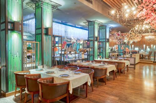 un restaurant avec des tables et des chaises dans une salle dans l'établissement Panarams Tashkent Hotel, a member of Radisson Individuals, à Tachkent