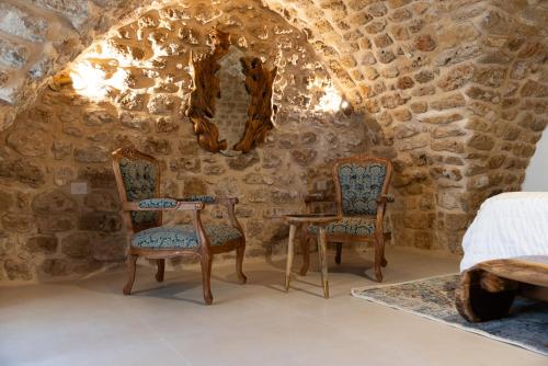 a bedroom with two chairs and a table in a stone wall at Zaroob Guest House in ‘Akko