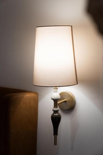 a lamp with a white shade on a wall at Zaroob Guest House in ‘Akko