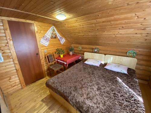 a bedroom in a log cabin with a bed and a table at Садиба Урочище Луг in Vorokhta