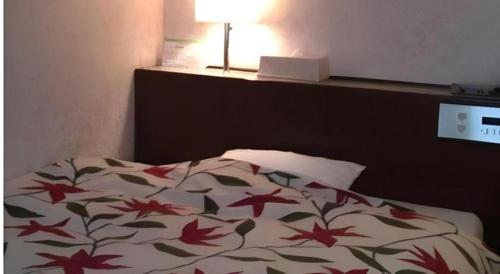 a bed with a blanket with red leaves on it at Sento Otani Hotel in Toyooka