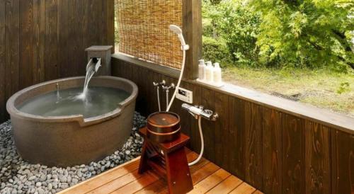 a bathroom with a bath tub with a window at Kyoto Keburikawa Hotel in Kameoka