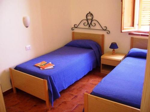 una camera con due letti con lenzuola blu di Residence Villaggio Smedile a Capo Vaticano
