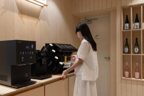 a woman standing in front of a coffee machine at Aank Ryokan Hotel Ansan Seonbu Branch in Ansan