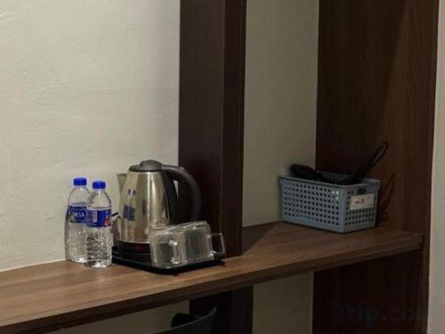 a wooden shelf with a coffee maker and bottles of water at Hotel Zamburger Bentong in Bentong