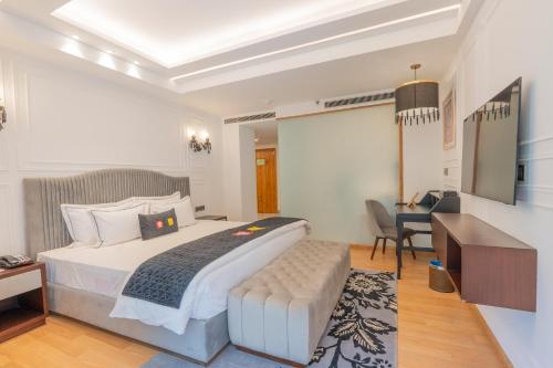 a hotel room with a large bed and a desk at Mastiff Select Mandavya Dharamkot, McLeodganj in Dharamshala