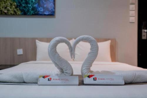 two swans shaped like hearts are on a bed at Kimal Hotel Taiping in Taiping