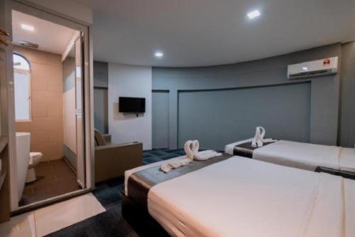 a hotel room with two beds and a mirror at Kimal Hotel Taiping in Taiping