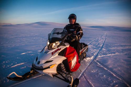 a man is riding a snowmobile in the snow at Tundrea Holiday Resort in Kilpisjärvi