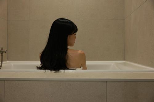 a woman sitting in a tub in a bathroom at Aank Ryokan Hotel Ansan Seonbu Branch in Ansan